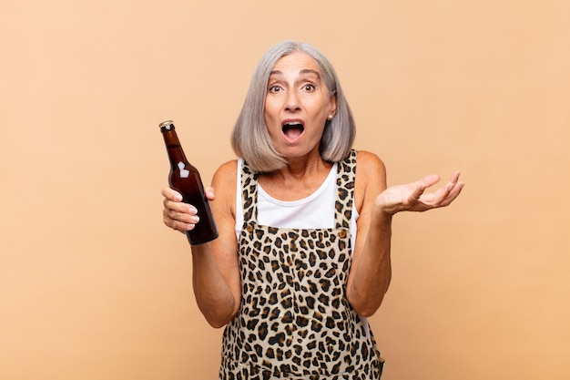 Mulher de meia idade sentindo-se extremamente chocada e surpresa, ansiosa e em pânico, com um olhar estressado e horrorizado com uma cerveja