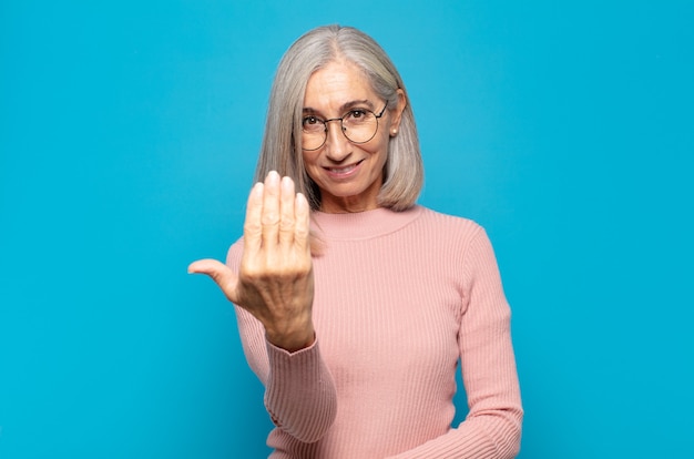 Mulher de meia-idade sentindo-se feliz, bem-sucedida e confiante, enfrentando um desafio e dizendo para você! ou dando boas-vindas a você