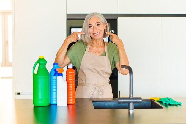 Mulher de meia-idade sorrindo com confiança apontando para seu próprio sorriso largo, atitude positiva, relaxada e satisfeita