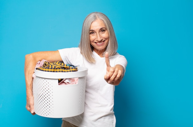 Mulher de meia-idade sorrindo com orgulho e confiança fazendo a pose número um triunfantemente, sentindo-se uma líder