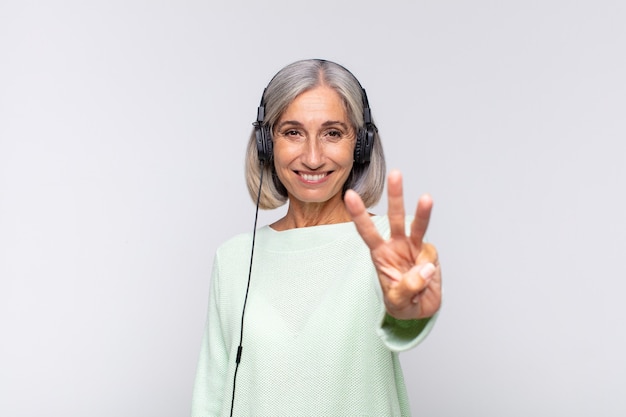 Mulher de meia idade sorrindo e parecendo amigável, mostrando o número três ou terceiro com a mão para a frente, em contagem regressiva. conceito de musica