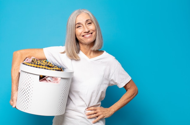 Mulher de meia-idade sorrindo feliz com uma mão no quadril e uma atitude confiante, positiva, orgulhosa e amigável