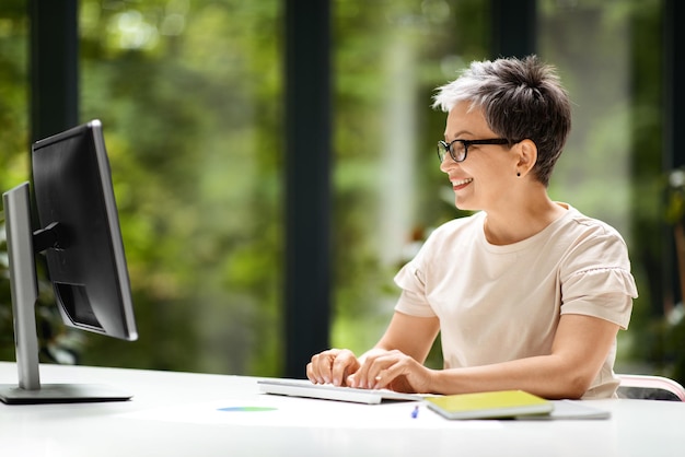 Mulher de meia idade trabalhando em home office no computador pc