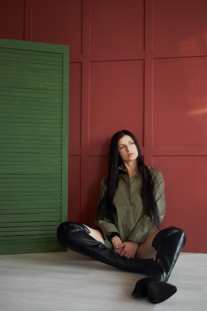 Mulher de moda com cabelo longo e pernas em botas de couro sorri emoções alegres