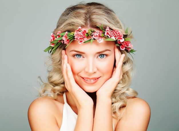Mulher de modelo de spa sorridente com pele limpa saudável, loira encaracolada e coroa de flores. Antecedentes antienvelhecimento e cosmetologia