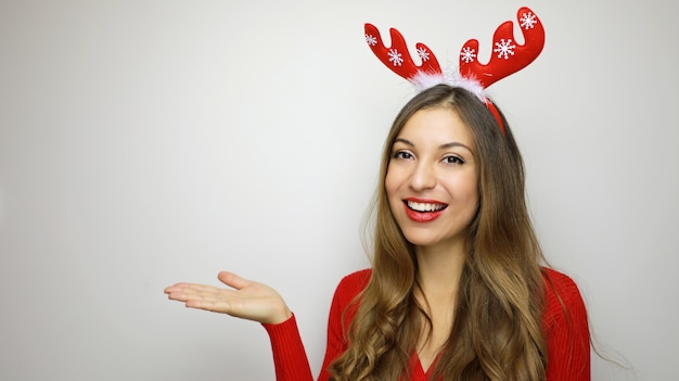 Mulher de Natal com chifres de rena mostrando seu produto nas mãos