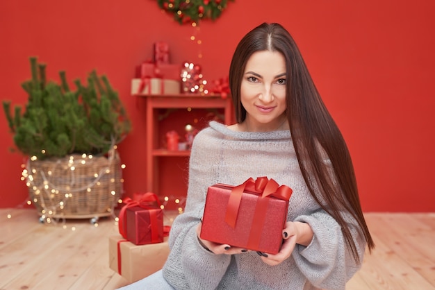 Mulher de Natal com presentes perto da árvore de Natal