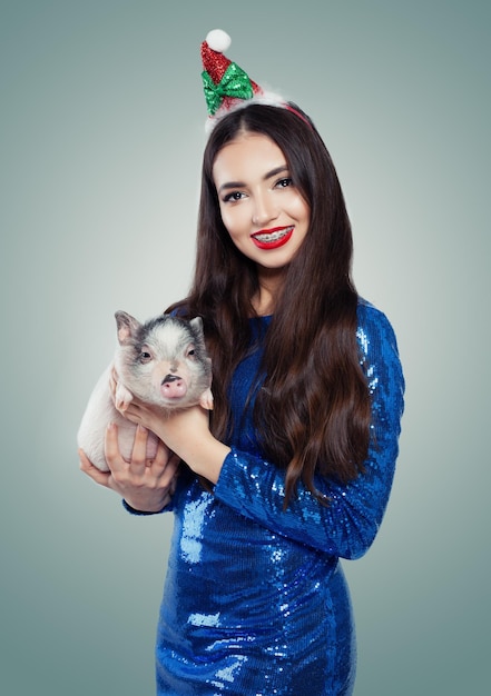 Mulher de Natal sorridente de vestido azul com porquinho Sorriso e dentes com aparelho