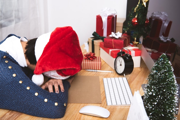 Mulher de negócio com chapéu de santa que dorme no escritório da mesa após a festa de natal e o ano novo feliz.