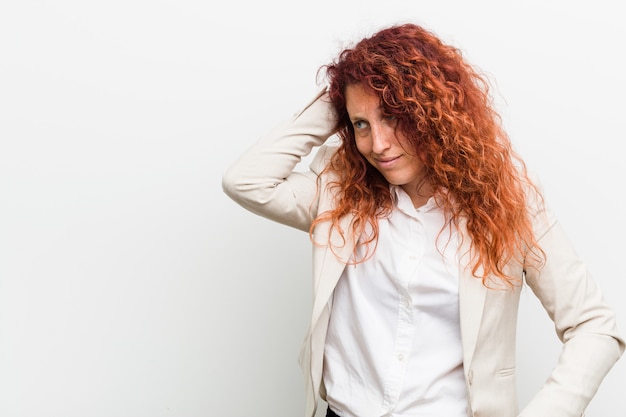 Mulher de negócio natural nova do ruivo isolada contra a parte traseira tocante branca da cabeça, pensando e fazendo uma escolha.