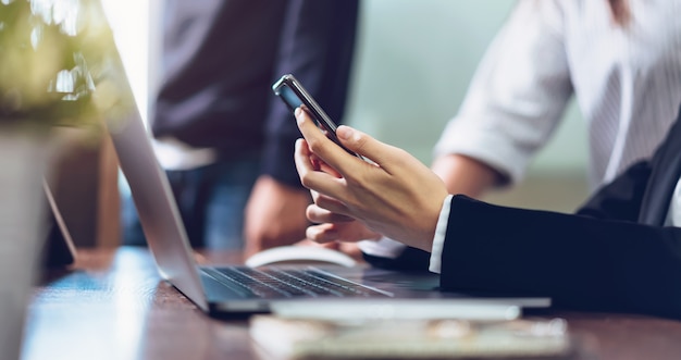 Mulher de negócio que guarda o smartphone, usando o telefone celular no escritório.