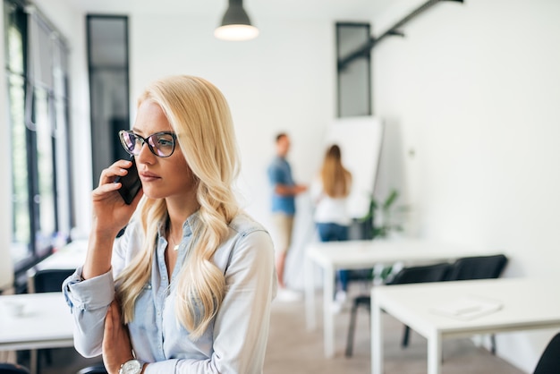 Mulher de negócio sério bonita que tem um telefonema no trabalho.