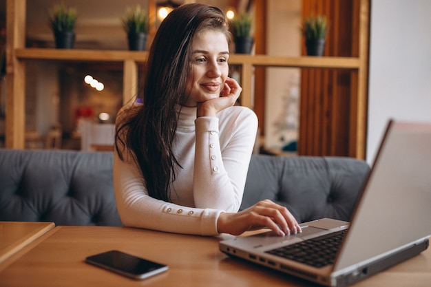 Mulher de negócio trabalhando em laptop e telefone em um café