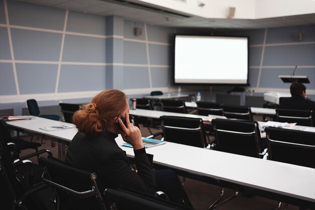 Mulher de negócios a falar por telemóvel numa conferência de negócios ou numa apresentação numa sala de conferências