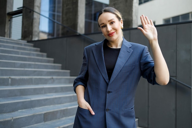 Mulher de negócios acenando com a mão no fundo de um edifício moderno