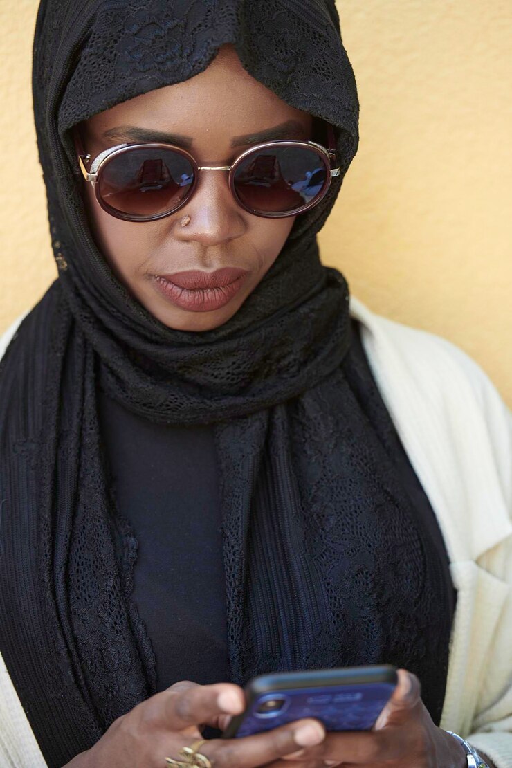 Foto mulher de negócios africana usando telefone inteligente vestindo roupas islâmicas tradicionais