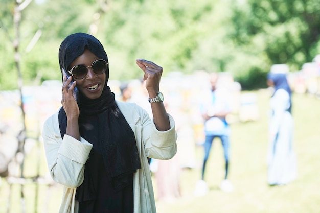 mulher de negócios africana usando telefone inteligente vestindo roupas islâmicas tradicionais