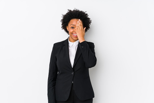 Mulher de negócios afro-americana com idade média em branco isolado se divertindo cobrindo metade do rosto com a palma da mão.