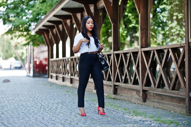 Mulher de negócios afro-americana elegante com bolsa nas ruas da cidade