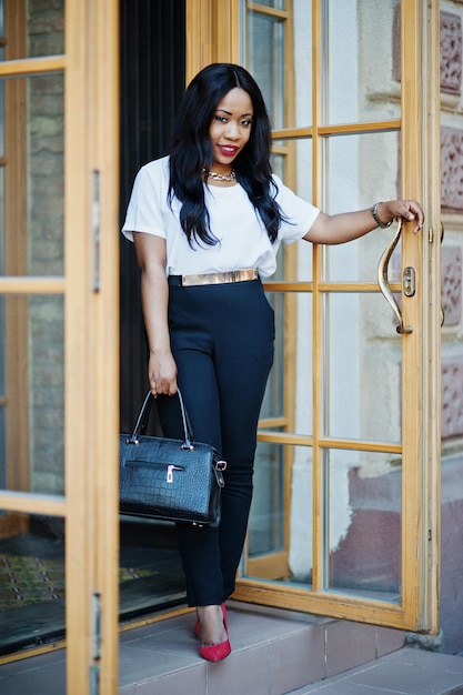 Mulher de negócios afro-americana elegante com bolsa nas ruas da cidade