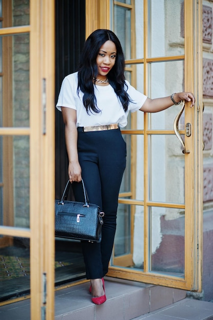 Mulher de negócios afro-americana elegante com bolsa nas ruas da cidade