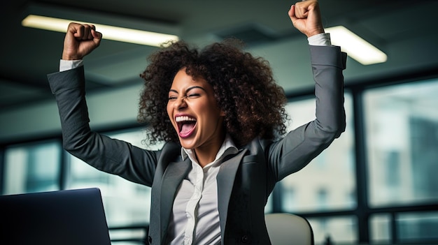 Mulher de negócios afro-americana entusiasmada no local de trabalho celebrando o negócio bem sucedido