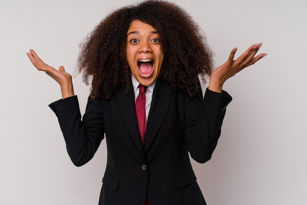 Mulher de negócios afro-americana jovem vestindo um terno isolado no branco, comemorando uma vitória ou sucesso, ele fica surpreso e chocado.