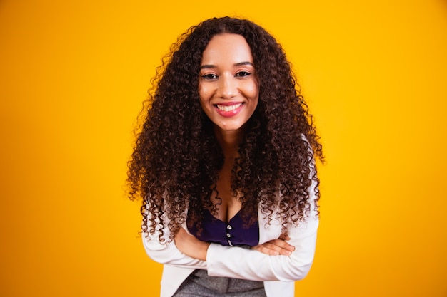 Mulher de negócios afro jovem com os braços cruzados, sorrindo, olhando para a câmera.