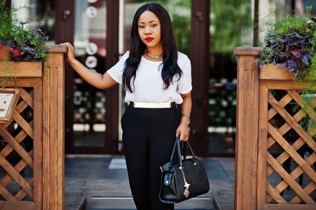 Mulher de negócios americano africano elegante com bolsa nas ruas da cidade.