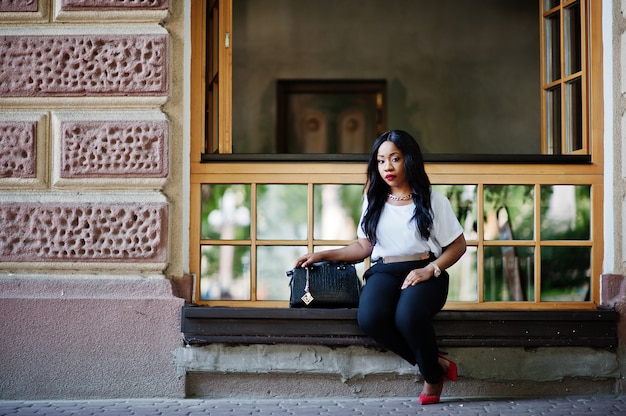 Mulher de negócios americano africano elegante com bolsa nas ruas da cidade.