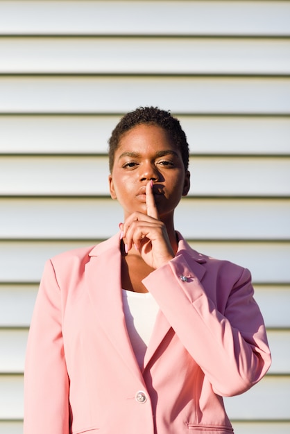 Mulher de negócios americano africano fazendo gesto de silêncio.