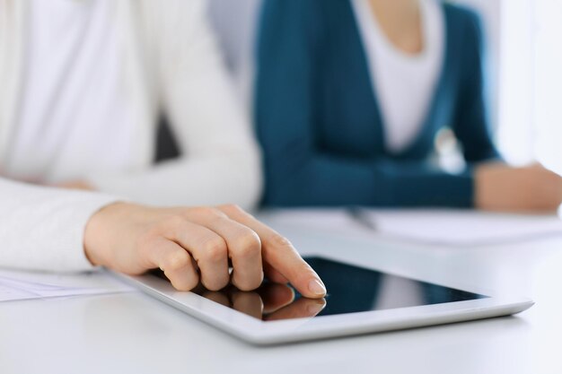 Mulher de negócios apontando para a tela do computador tablet enquanto faz uma apresentação para sua colega