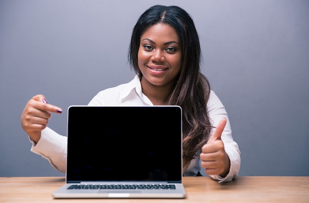 Mulher de negócios apontando para a tela em branco do laptop