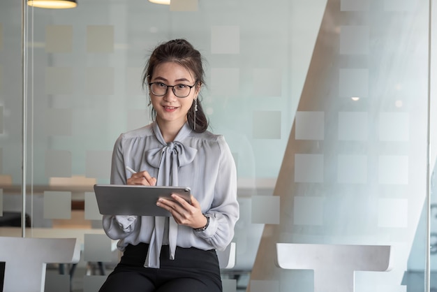 Mulher de negócios asiática à espera de uma feliz entrevista de emprego no escritório com um tablet.