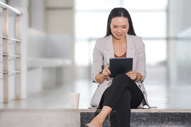 Mulher de negócios asiática adulta usando computador tablet digital e escritório trabalhando ao ar livre