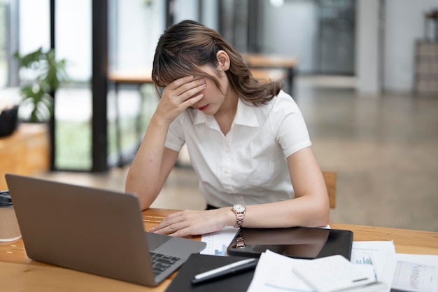 Mulher de negócios asiática cansada com dor de cabeça no escritório sentindo-se doente no espaço de cópia de trabalho