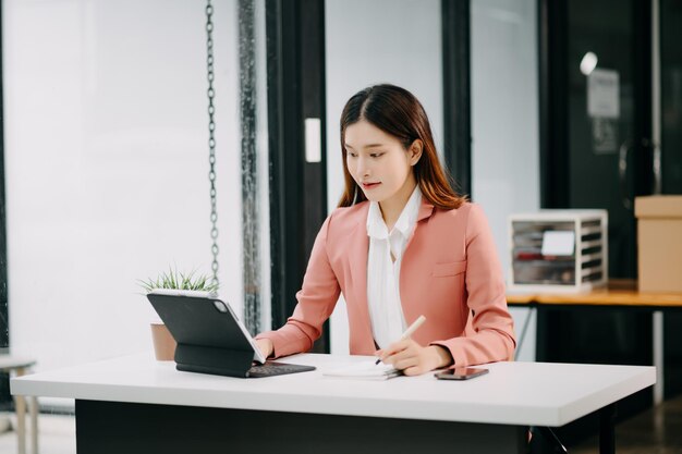 Mulher de Negócios Asiática de Sucesso Analisando Finanças em Tablet e Laptop em Modern Office Desk Relatório de Impostos Estatísticas de Contabilidade e conceito de pesquisa analíticaxA