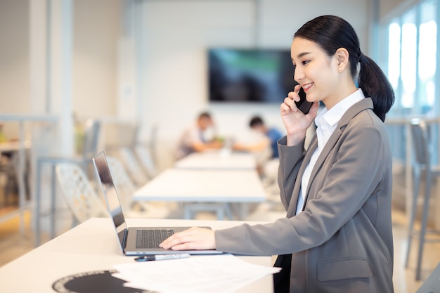 Mulher de negócios asiática feliz falando ao celular