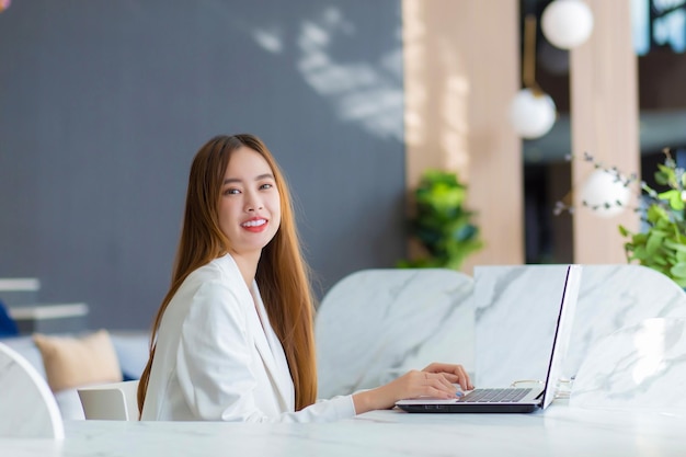 Mulher de negócios asiática jovem trabalhando em um espaço de coworking com a papelada do laptop Conceito de mulher de negócios