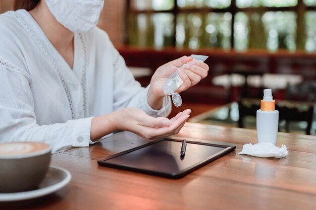 Mulher de negócios asiática limpando a mão e o computador antes de woking online. Distanciamento social e novo estilo de vida normal.