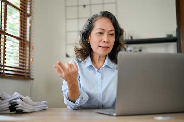 Mulher de negócios asiática profissional olhando para a tela do laptop trabalhando em sua mesa