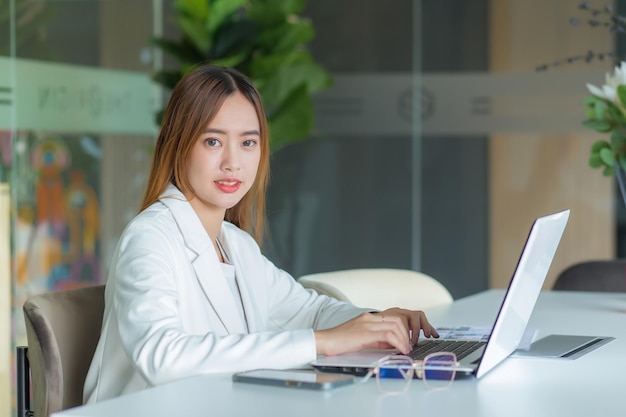 Mulher de negócios asiática trabalha em um espaço de co-working com a papelada do laptop (conceito de mulher de negócios.)