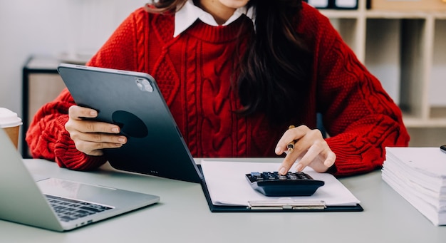 Mulher de negócios asiática usando calculadora e laptop para fazer finanças matemáticas em uma mesa de escritório relatório de impostos estatísticas contábeis e conceito de pesquisa analítica