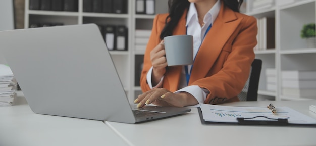 Mulher de negócios asiática usando computador portátil e trabalhando no escritório com documento de calculadora na mesa fazendo planejamento analisando o conceito de análise de finanças de investimento de plano de negócios de relatório financeiro