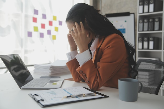 Mulher de negócios asiática usando computador portátil e trabalhando no escritório com documento de calculadora na mesa fazendo planejamento analisando o conceito de análise de finanças de investimento de plano de negócios de relatório financeiro