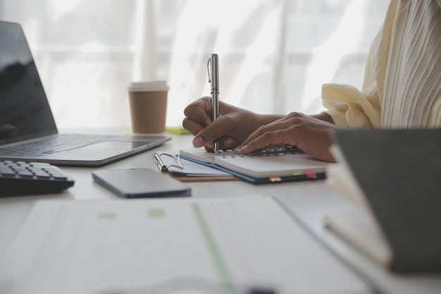 Mulher de negócios asiática usando computador portátil e trabalhando no escritório com documento de calculadora na mesa fazendo planejamento analisando o conceito de análise de finanças de investimento de plano de negócios de relatório financeiro