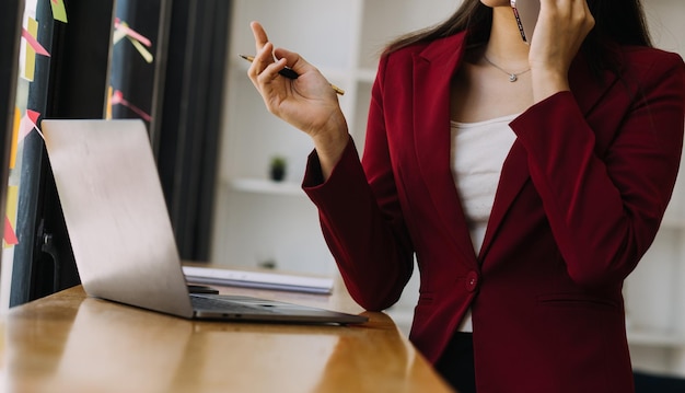 Mulher de negócios asiática usando computador portátil e trabalhando no escritório com documento de calculadora na mesa fazendo planejamento analisando o conceito de análise de finanças de investimento de plano de negócios de relatório financeiro