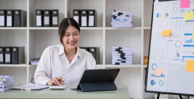 Mulher de negócios asiática usando computador portátil e trabalhando no escritório com documento de calculadora na mesa fazendo planejamento analisando o conceito de análise de finanças de investimento de plano de negócios de relatório financeiro