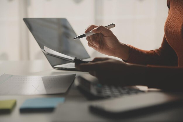 Foto mulher de negócios asiática usando computador portátil e trabalhando no escritório com documento de calculadora na mesa fazendo planejamento analisando o relatório financeiro plano de negócios conceito de análise de finanças de investimento