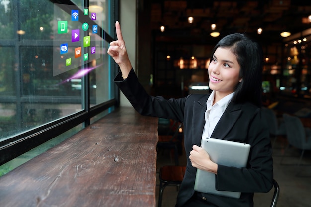 Mulher de negócios asiático usando computador portátil na mesa no café e tocar no ícone do computador no ar